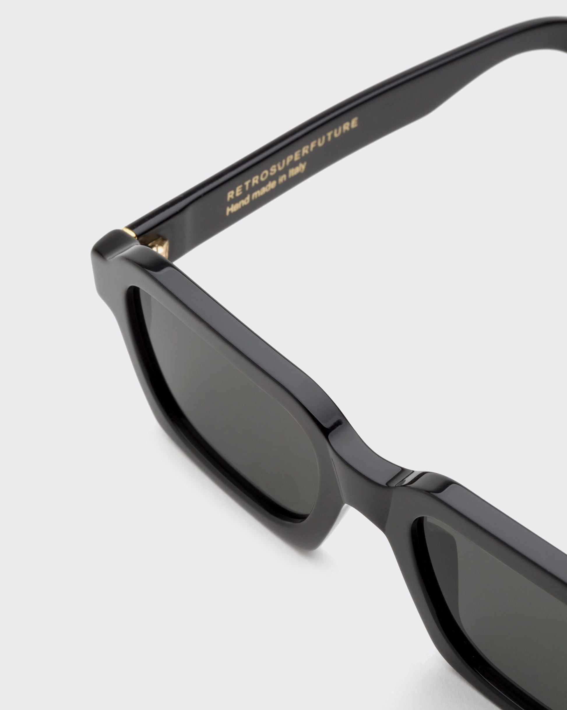 Black sunglasses with 'Retrosuperfuture' branding on a light gray background
