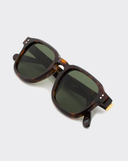 Sunglasses with tortoiseshell frame and dark lenses on a light gray background