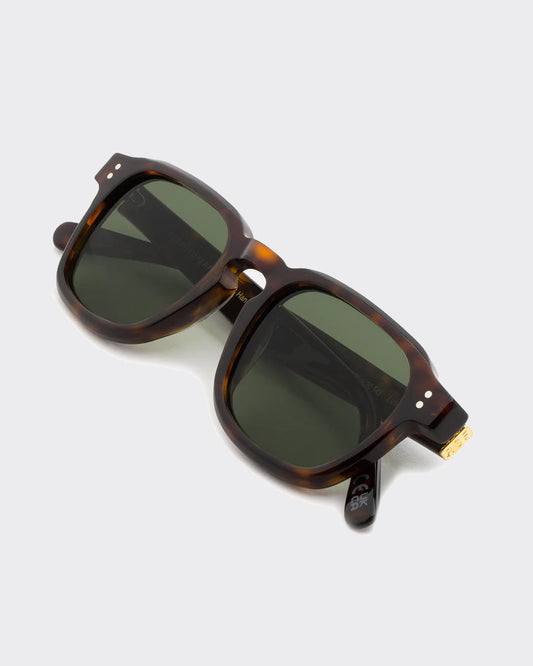 Sunglasses with tortoiseshell frame and dark lenses on a light gray background