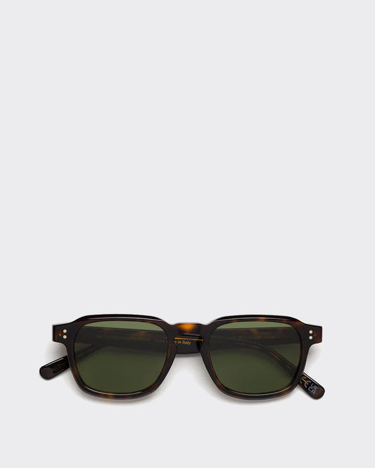 Sunglasses with tortoiseshell frame and green lenses on a light gray background